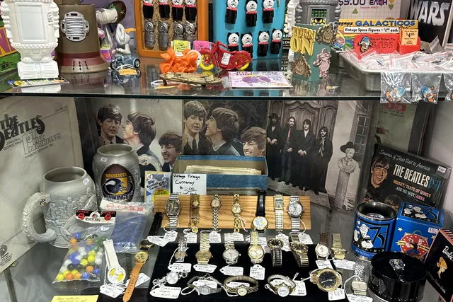 A glass case holding watches, pocket knives, badges and boxed collectibles