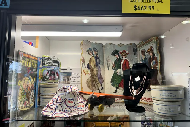 A glass case of vintage paper, jewelry and boxed toys