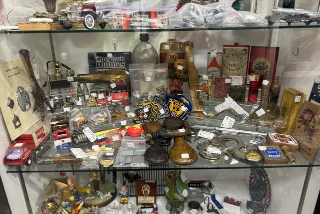 Books, tools and small antiques arranged on the shelves of a glass case