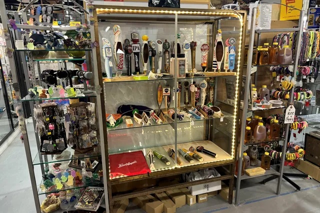 Beer tap handles and small collectibles in a lit glass display cabinet