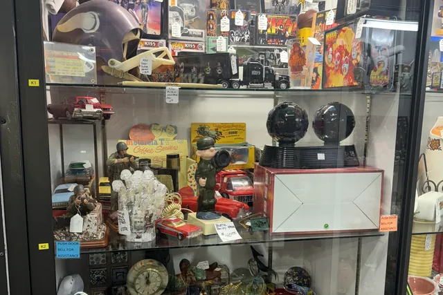A lit glass case packed with figurines, clocks and curiosities