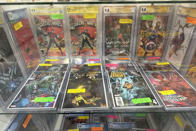 Graded Secret Wars and Spider-Man comics in sealed cases, laid out in a glass counter