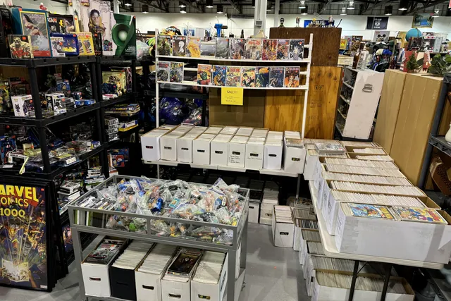 Longboxes of raw comics on tables beneath a Marvel poster