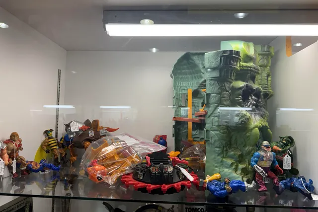 Loose vintage action figures and a green playset inside a glass case