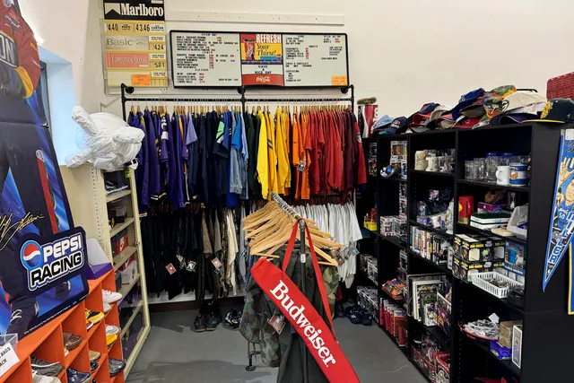 Racks of vintage clothing beside pennants and a Budweiser sign