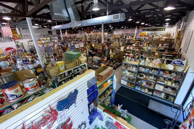 A broad aisle of display cases and shelving under the warehouse roof