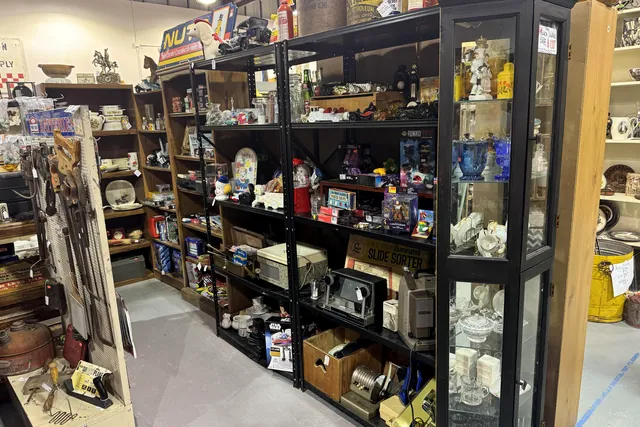 A booth of black shelving and a glass cabinet beside the aisle