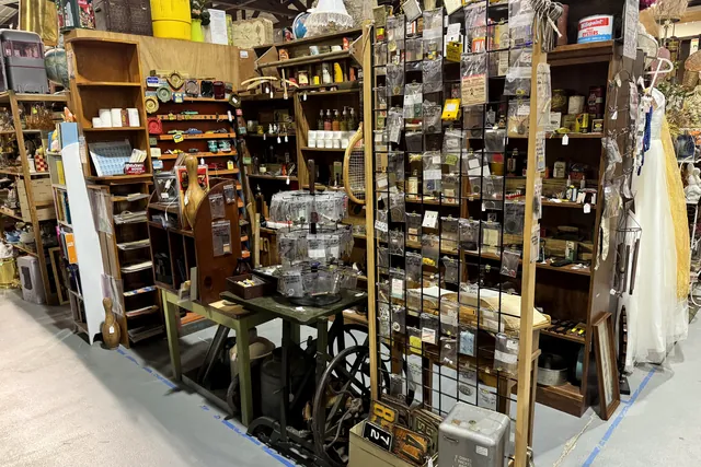 An aisle of wooden shelving stacked with cabinets, bottles and tools