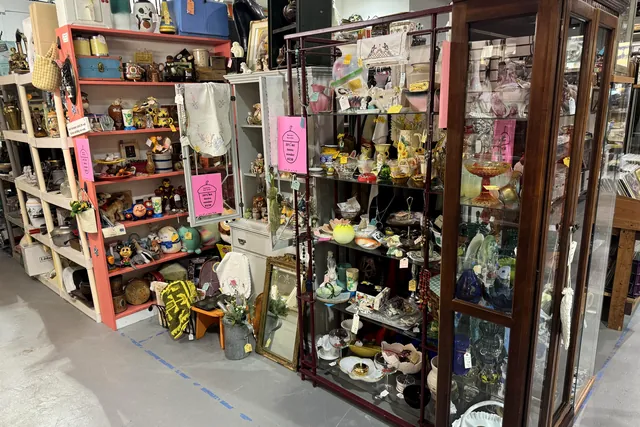 An aisle of loaded shelves running beside a tall glass cabinet