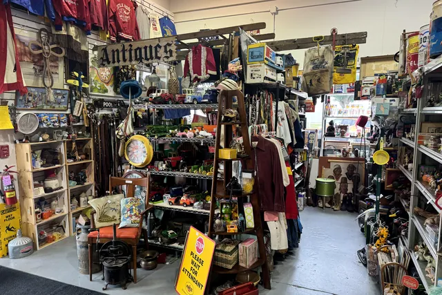 A booth under an Antiques banner, with clothing, cast iron and lamps