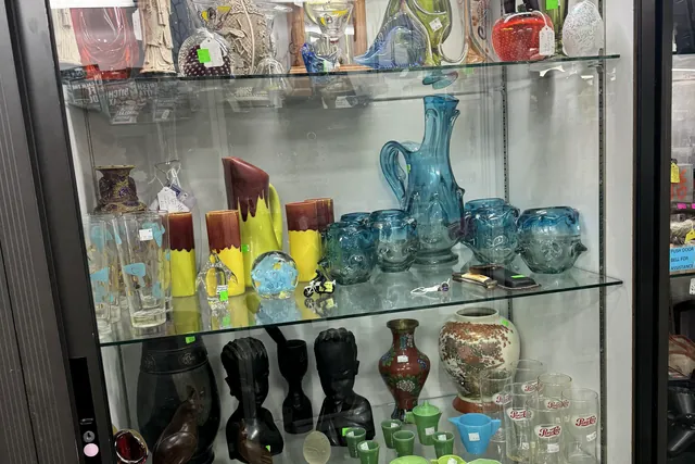 Colored glass vases and pottery arranged on lit glass shelves