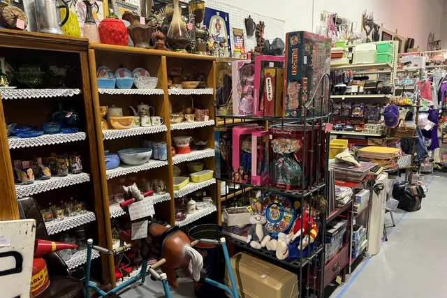 Shelves of pottery and stoneware beside lace and household goods