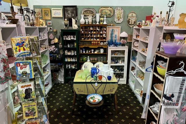 A booth of white shelving filled with figurines, glassware and china