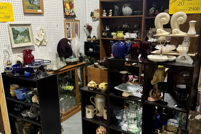 Pottery and collectibles on dark shelving against a pegboard wall