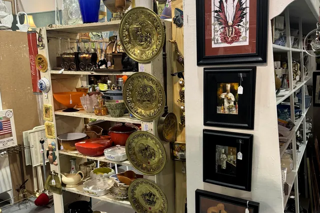 Framed pictures and decorative plates displayed on open shelving