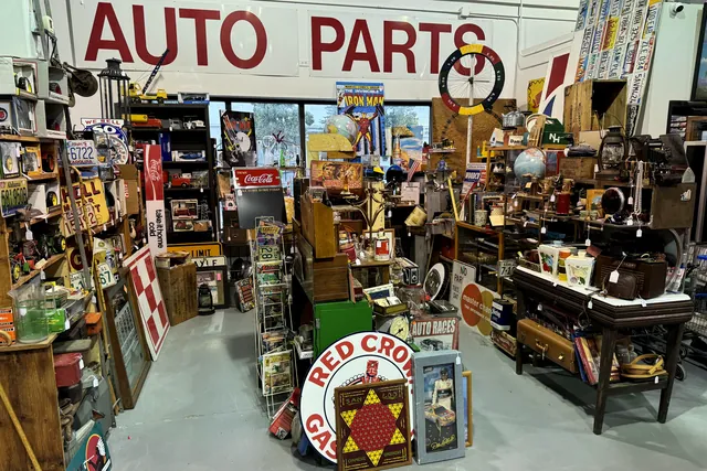 A booth of petroliana under a painted Auto Parts sign, with a Red Crown Gasoline sign in front