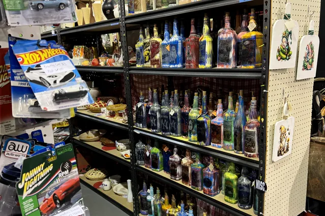 Hot Wheels and diecast cars hanging on pegs beside a shelf of colored bottles