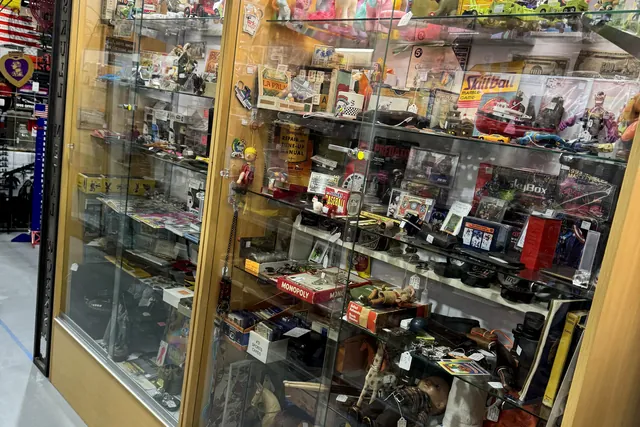 A long glass counter filled with diecast models, with license plates displayed above it