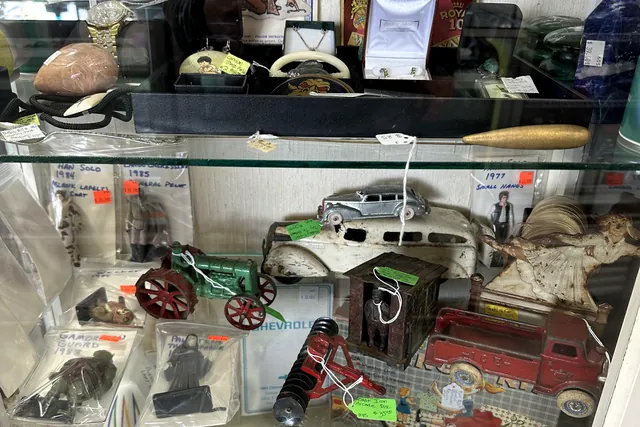 Cast iron trucks and farm toys inside a lit display case