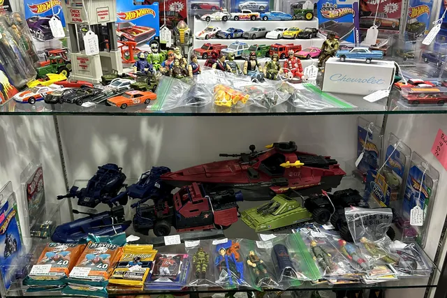 Carded Hot Wheels and loose toys on the shelves of a glass case